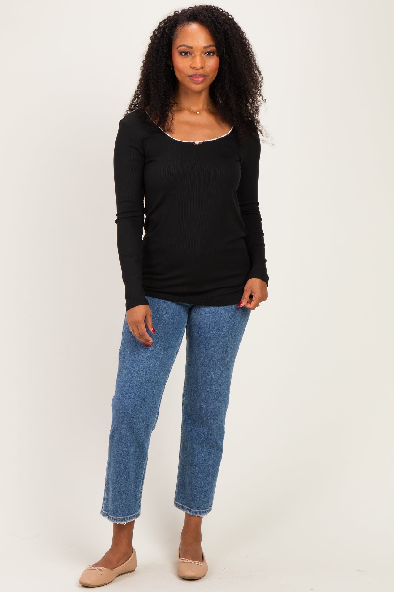 woman wearing a black long sleeve top and blue cropped jeans with beige flats