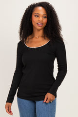 woman wearing a black long sleeve top with a scoop neckline and a decorative trim, styled with blue jeans