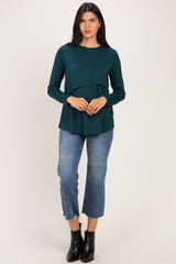 woman wearing a dark green long sleeve top with a tiered design and blue cropped jeans