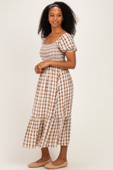 woman wearing a brown and white checked midi dress with puff sleeves and a tiered skirt