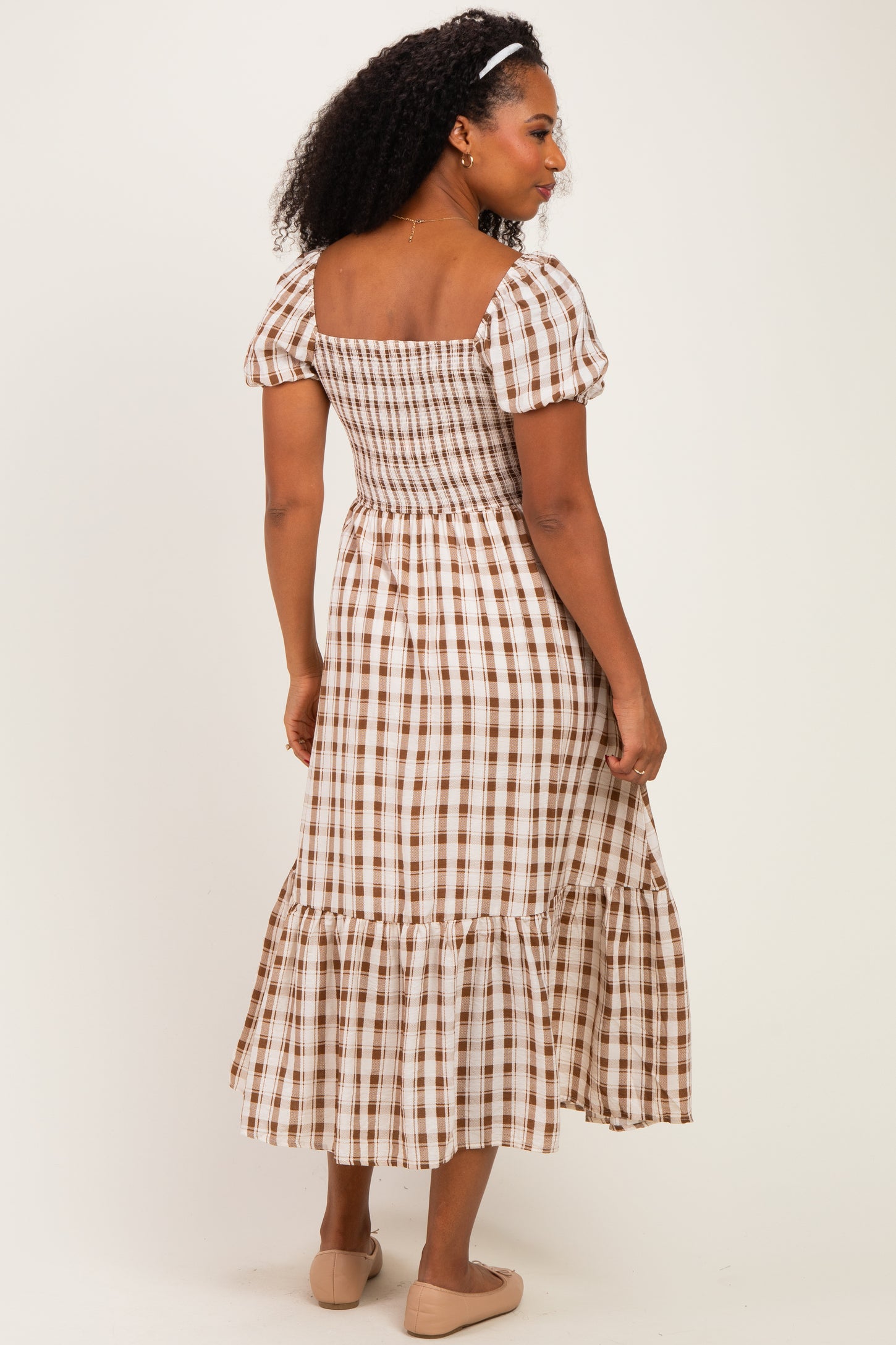 woman wearing a brown and white checked puff sleeve midi dress with a smocked bodice and tiered skirt