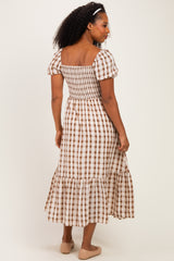 woman wearing a brown and white checked puff sleeve midi dress with a smocked bodice and tiered skirt