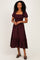 woman wearing a burgundy and black plaid maxi dress with puff sleeves and a smocked bodice
