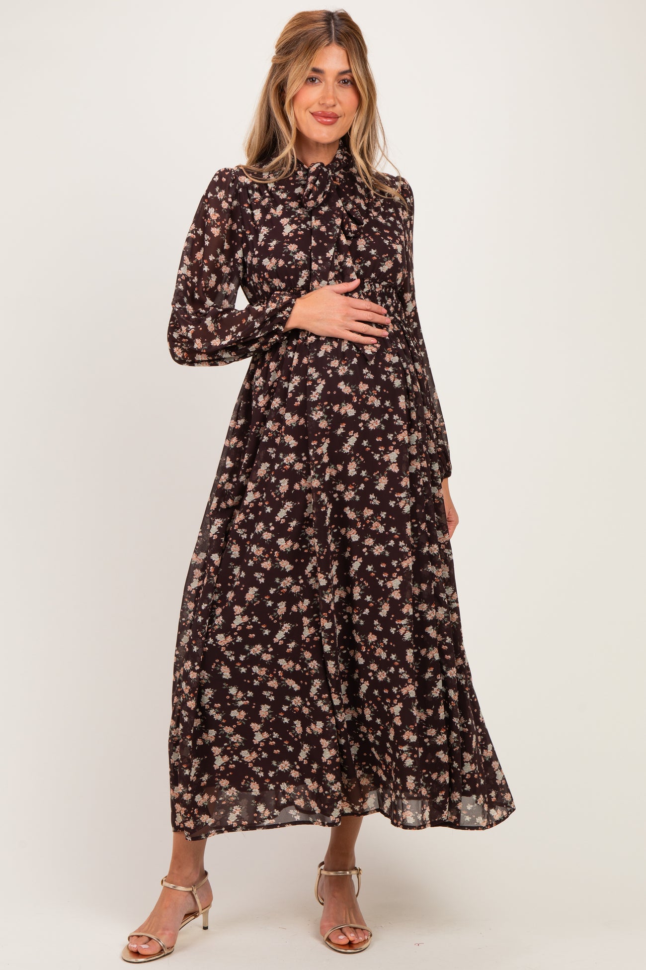 woman wearing a black floral maternity maxi dress and holding her baby bump