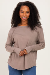 woman wearing a taupe long sleeve top with a relaxed fit and braided detail on the shoulders