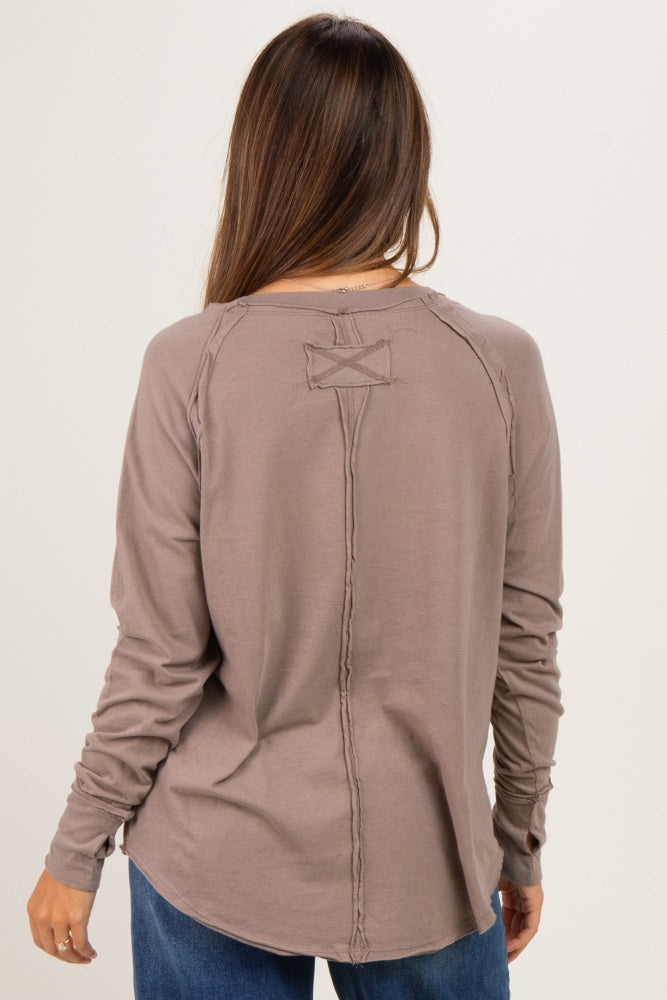woman wearing a brown long sleeve maternity top with stitched details and a curved hem