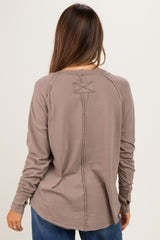 woman wearing a brown long sleeve maternity top with stitched details and a curved hem