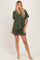 woman wearing an olive green short sleeve button-up pajama set with white trim and matching shorts