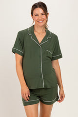 woman wearing a dark green maternity pajama set with short sleeves and shorts, showing her baby bump