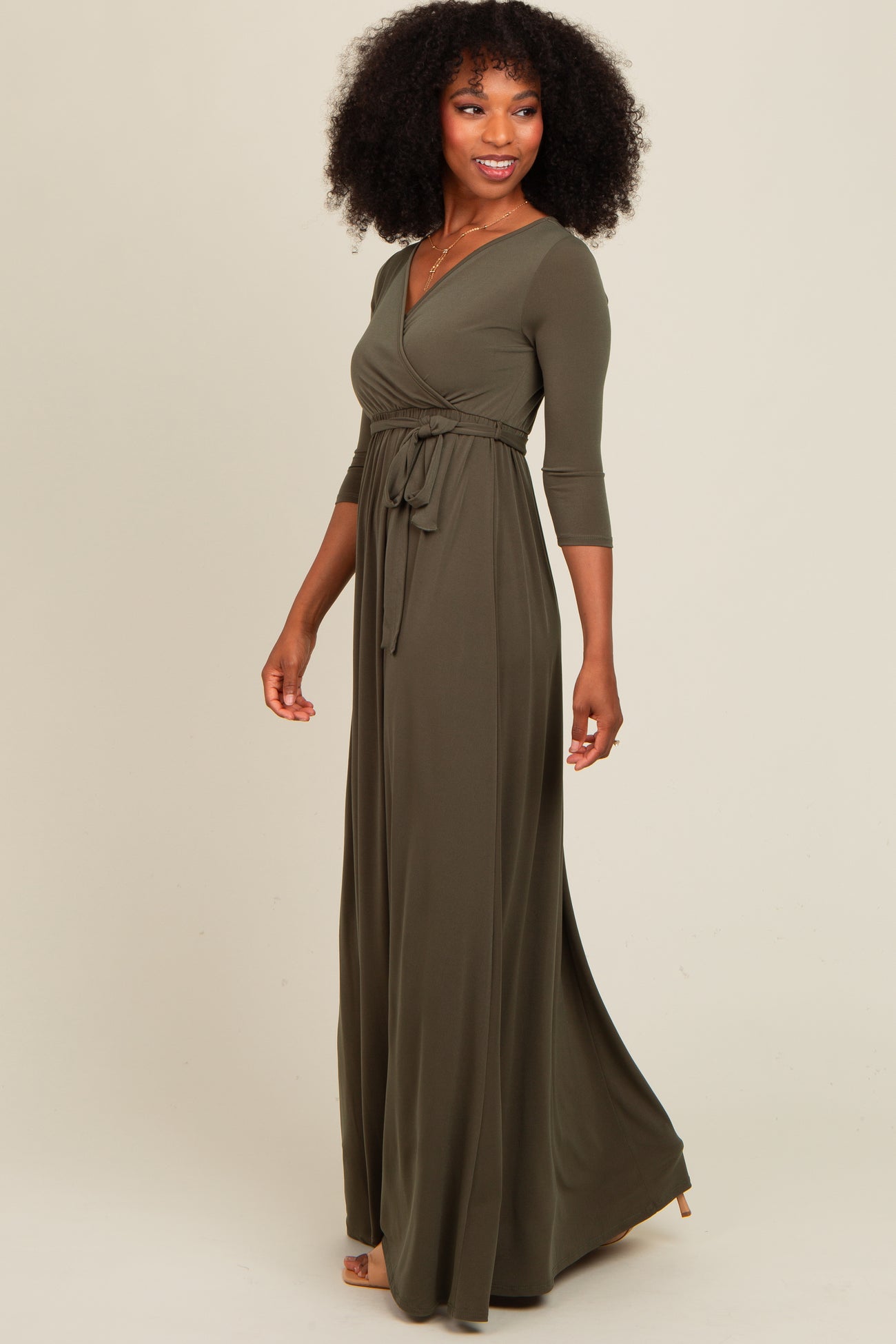 woman wearing a long olive green wrap dress with three-quarter sleeves and a tied waist