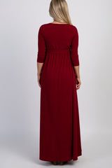 woman wearing a long burgundy maternity dress with three-quarter sleeves and a cinched waist from the back