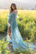 woman wearing a sheer mint green lace maternity gown, showcasing her baby bump in a field of tall grass