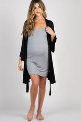woman wearing a black maternity dress, sitting and cradling her baby bump while in a cozy nursery setting