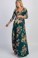 woman wearing a green floral maternity maxi dress with three-quarter sleeves and a visible baby bump
