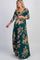woman wearing a green floral maternity maxi dress with three-quarter sleeves and a visible baby bump