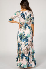 woman wearing a long floral maternity dress with three-quarter sleeves and a flowy skirt, showing a baby bump from the back