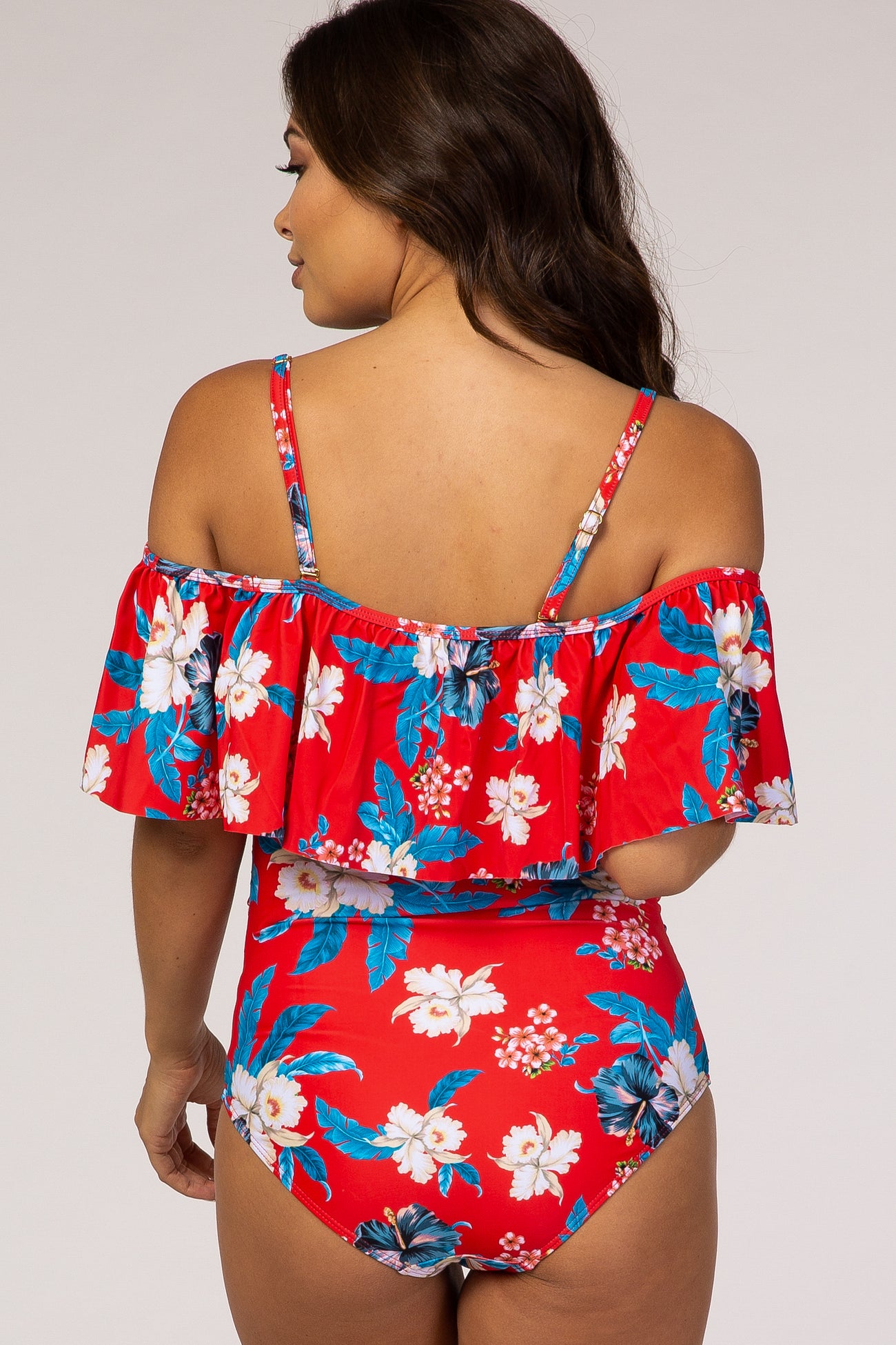 woman wearing a red floral off-the-shoulder maternity swimsuit with ruffle detailing and a printed design