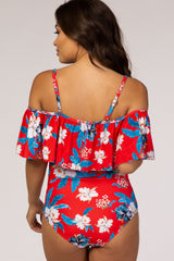 woman wearing a red floral off-the-shoulder maternity swimsuit with ruffle detailing and a printed design