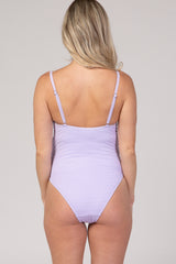 woman wearing a light lavender maternity swimsuit with adjustable straps and a fitted design, showing her back