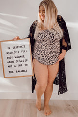 woman wearing a leopard print maternity top and black lace kimono, holding a sign about needing a massage and vacation