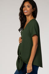 Smiling pregnant woman wearing a forest green short sleeve maternity top with a front tie detail