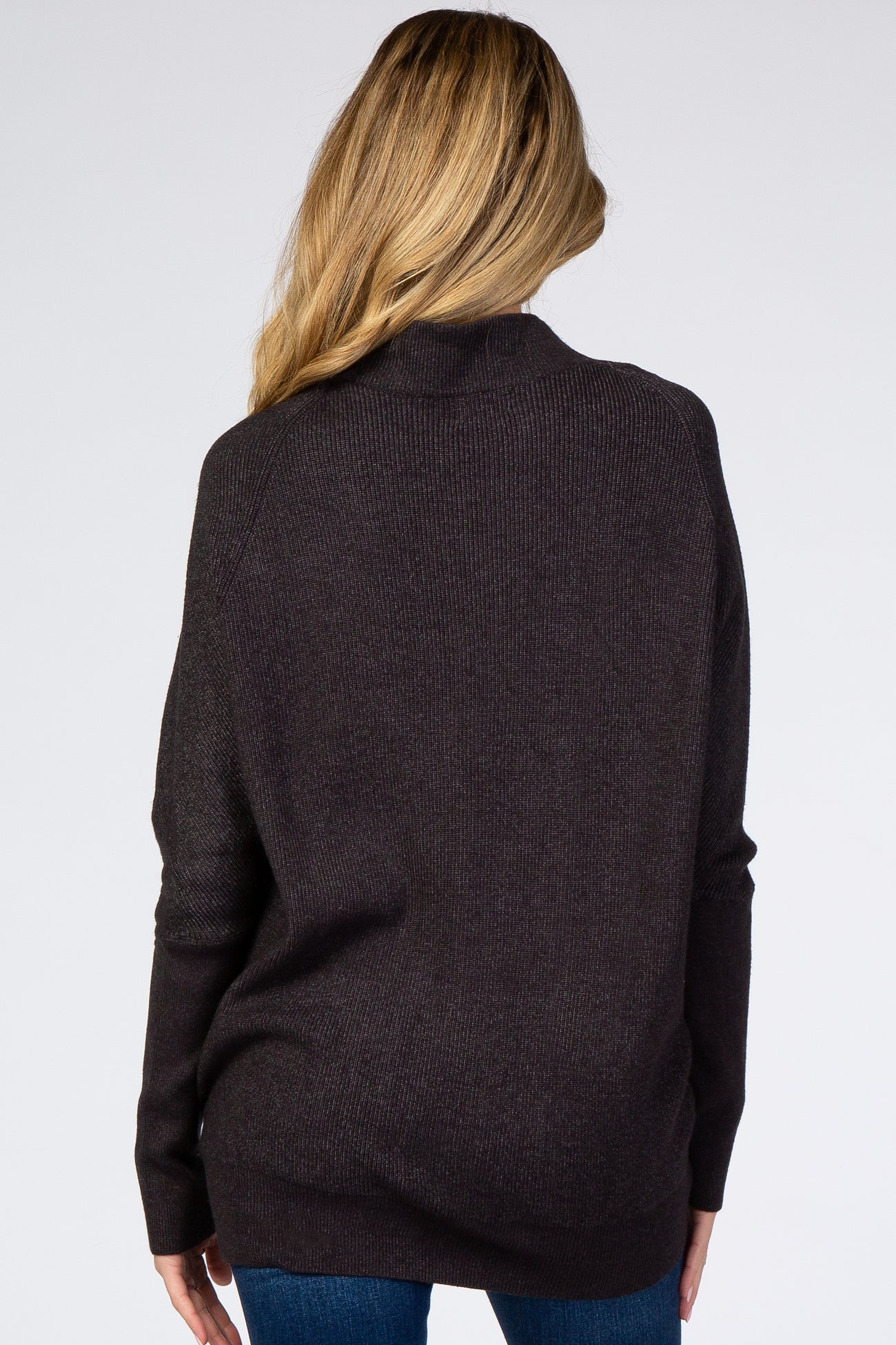 woman wearing a dark brown oversized maternity sweater, viewed from the back, paired with blue jeans