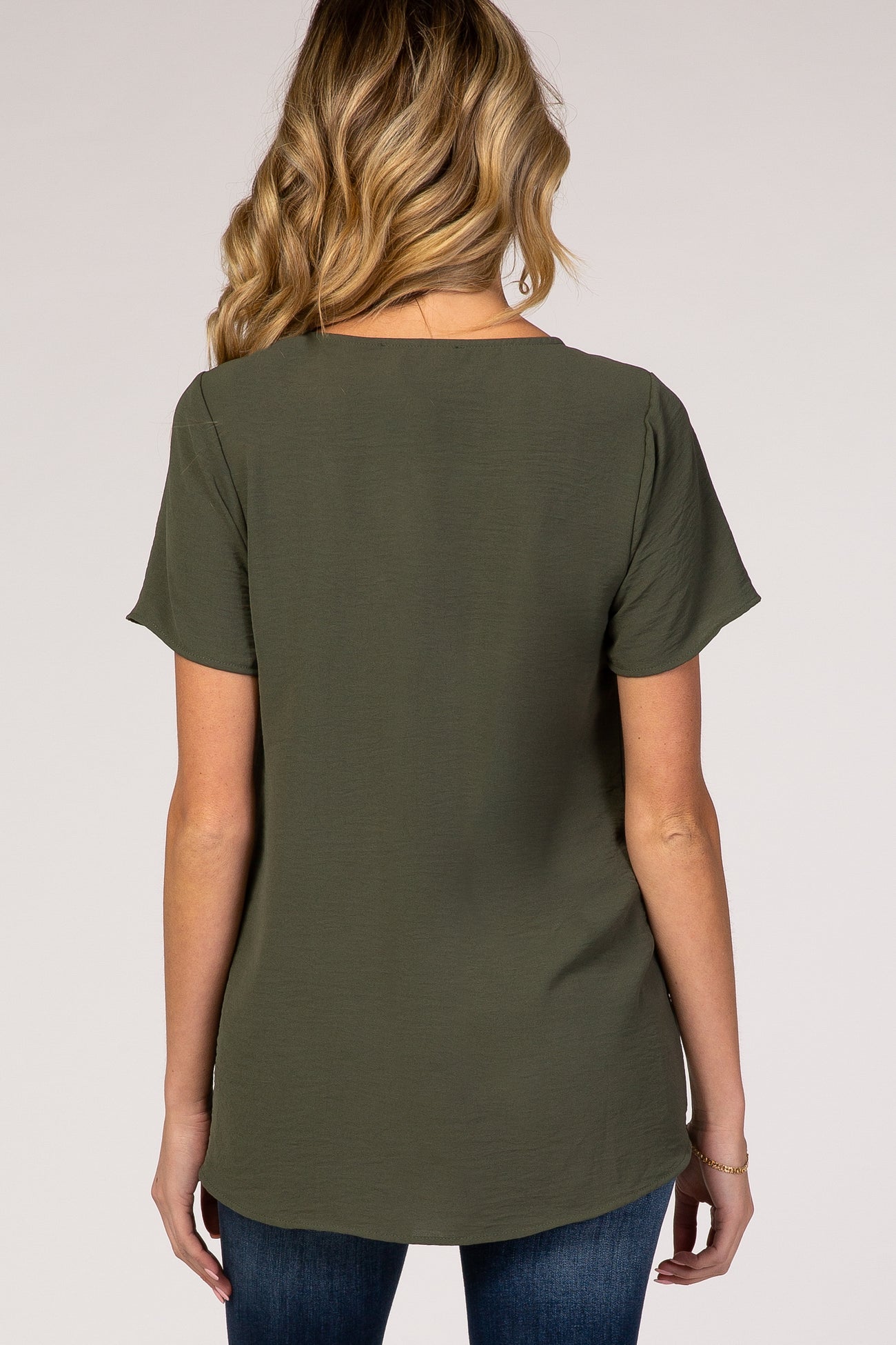 woman wearing a dark green short sleeve maternity top, viewed from the back