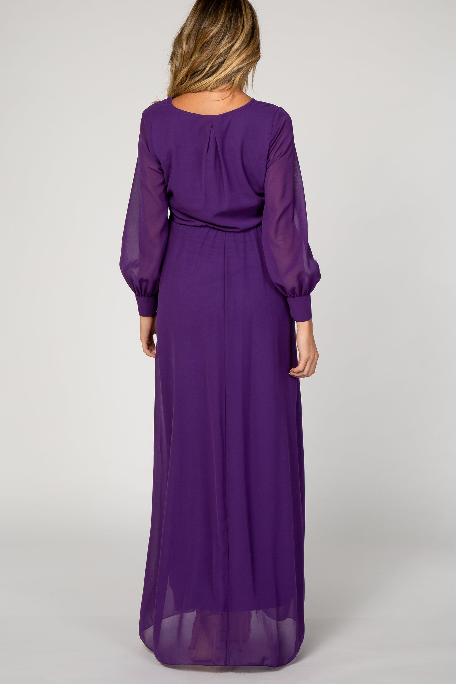 woman wearing a purple long sleeve maternity dress with a flowing skirt and sheer sleeves, showing the back view