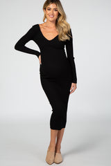 woman wearing a black ribbed maternity dress with a deep v-neckline and long sleeves, showing off her baby bump