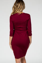 woman wearing a burgundy fitted maternity dress with three-quarter sleeves from the back