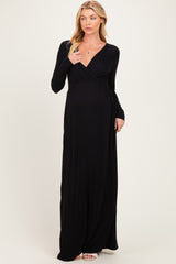 woman wearing a long black maternity dress with a deep v-neck and long sleeves, showcasing her baby bump