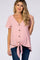 woman wearing a pink maternity top with a v-neck, button details, and a front tie, styled with dark jeans