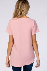 back view of a woman with blonde hair wearing a light pink short sleeve blouse and dark blue jeans