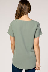 woman wearing a light green short sleeve maternity top, viewed from the back with a relaxed fit