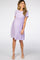 woman wearing a lavender short sleeve maternity dress with a textured pattern and a fitted waist, showing her baby bump