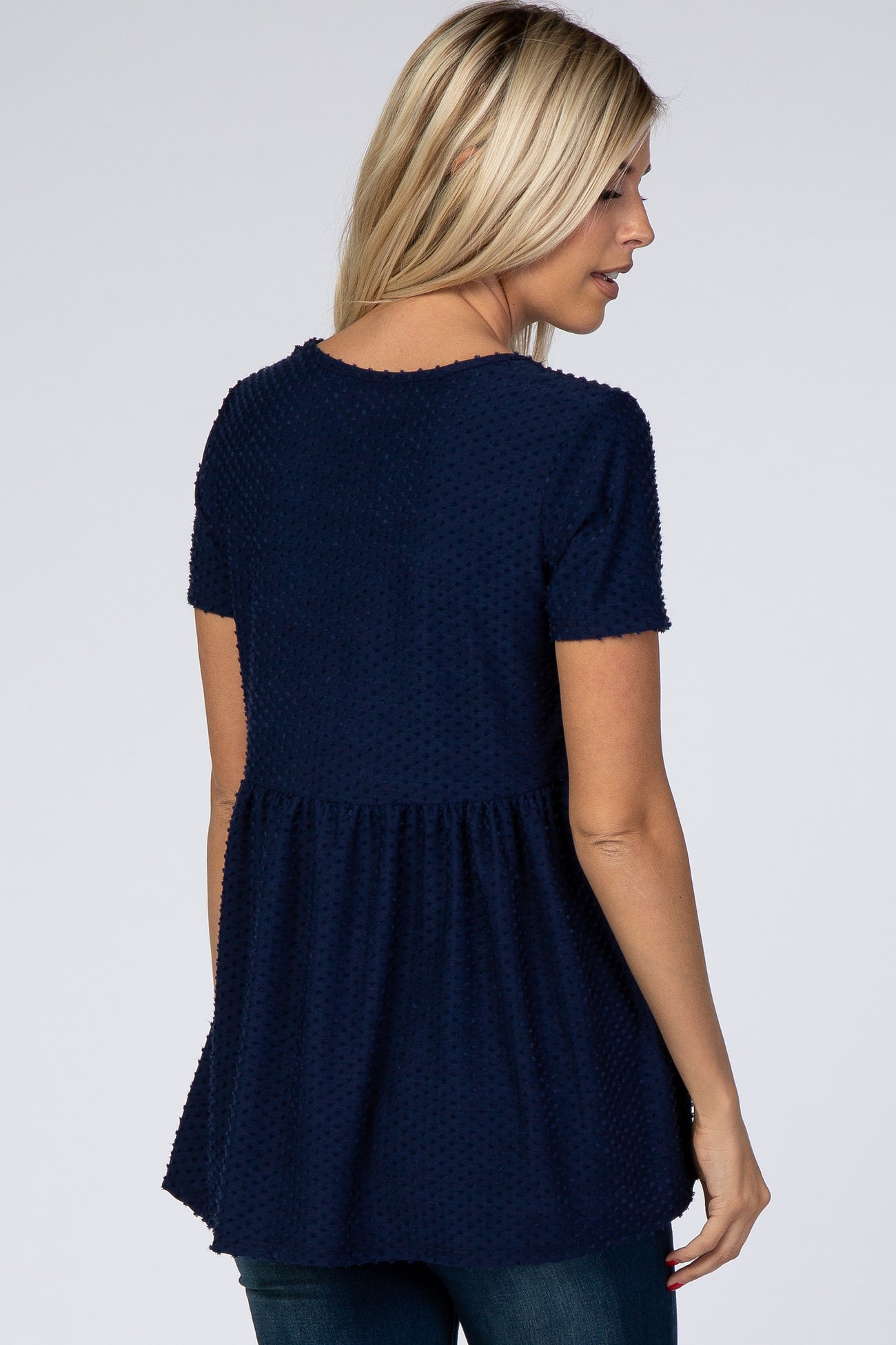 woman wearing a dark navy short sleeve peplum top with textured fabric, shown from the back