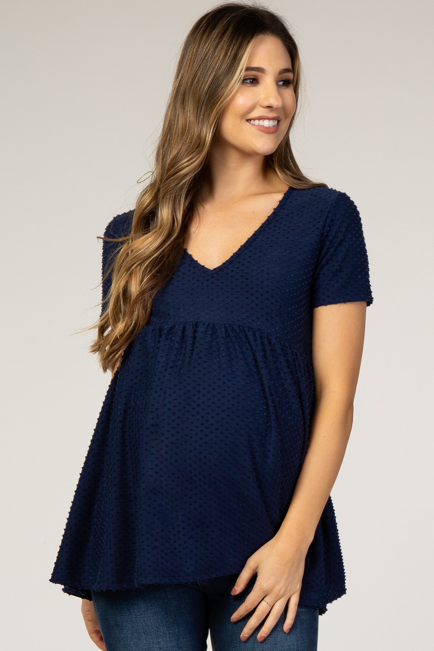 woman wearing a navy blue maternity top with a textured design and a flowy fit, showing her baby bump