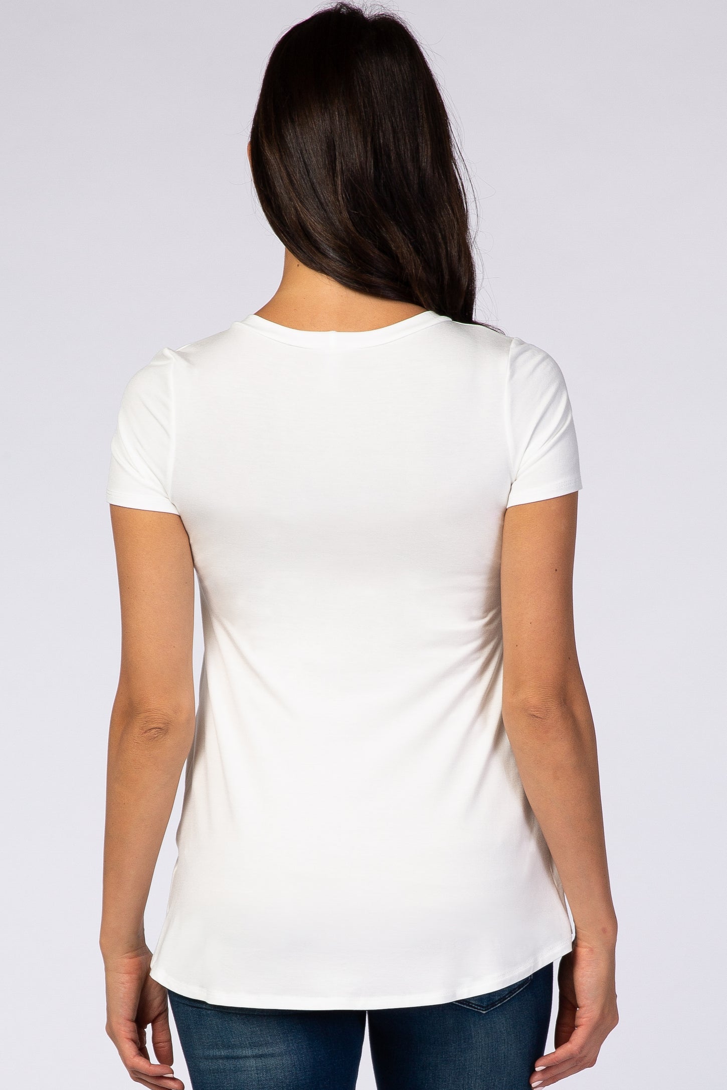 woman seen from the back wearing a white short sleeve t-shirt with a curved hem and blue jeans