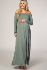 woman wearing a sage green off-the-shoulder maternity maxi dress and holding her baby bump