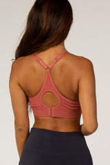 woman wearing a rose pink sports bra with a round cutout back and crisscross straps