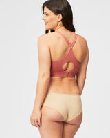woman wearing a rose-colored maternity bra with a racerback design and keyhole detail, paired with beige maternity brief underwear