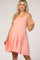 woman wearing a peach maternity swing dress with tiered details and adjustable straps, showcasing her baby bump