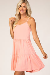woman wearing a coral sleeveless tiered swing dress and smiling