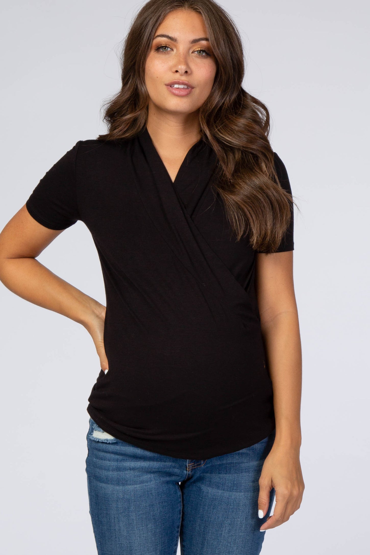 woman wearing a black short sleeve maternity top with a wrap design and a visible baby bump