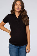 woman wearing a black short sleeve maternity top with a wrap design and a visible baby bump