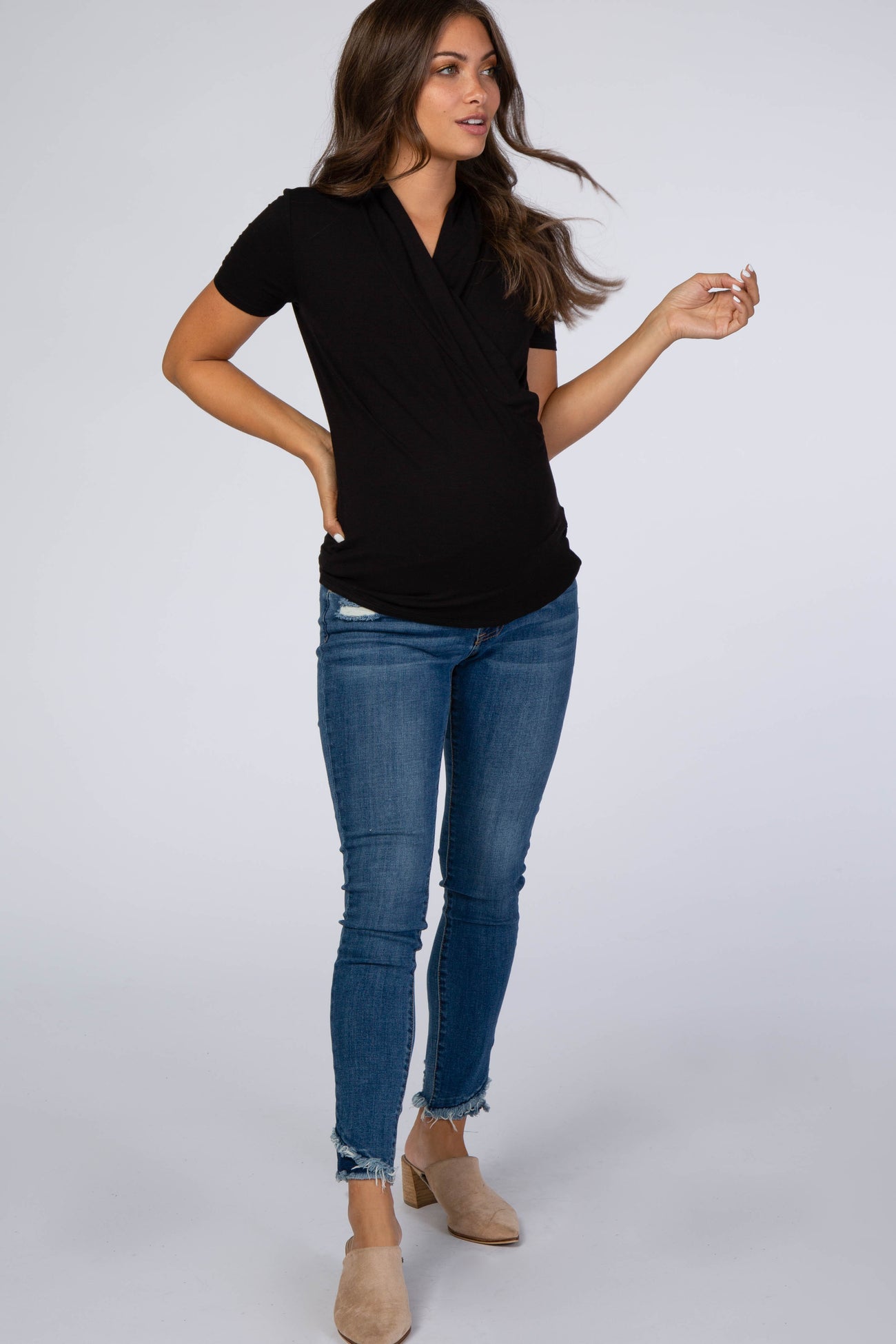 pregnant woman wearing a black short sleeve wrap maternity top and blue skinny jeans