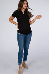 pregnant woman wearing a black short sleeve wrap maternity top and blue skinny jeans