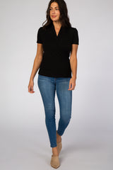 woman wearing a black short sleeve wrap top and blue skinny jeans with beige heels