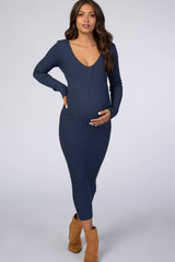 woman wearing a navy ribbed maternity dress with a v-neck and long sleeves, holding her baby bump