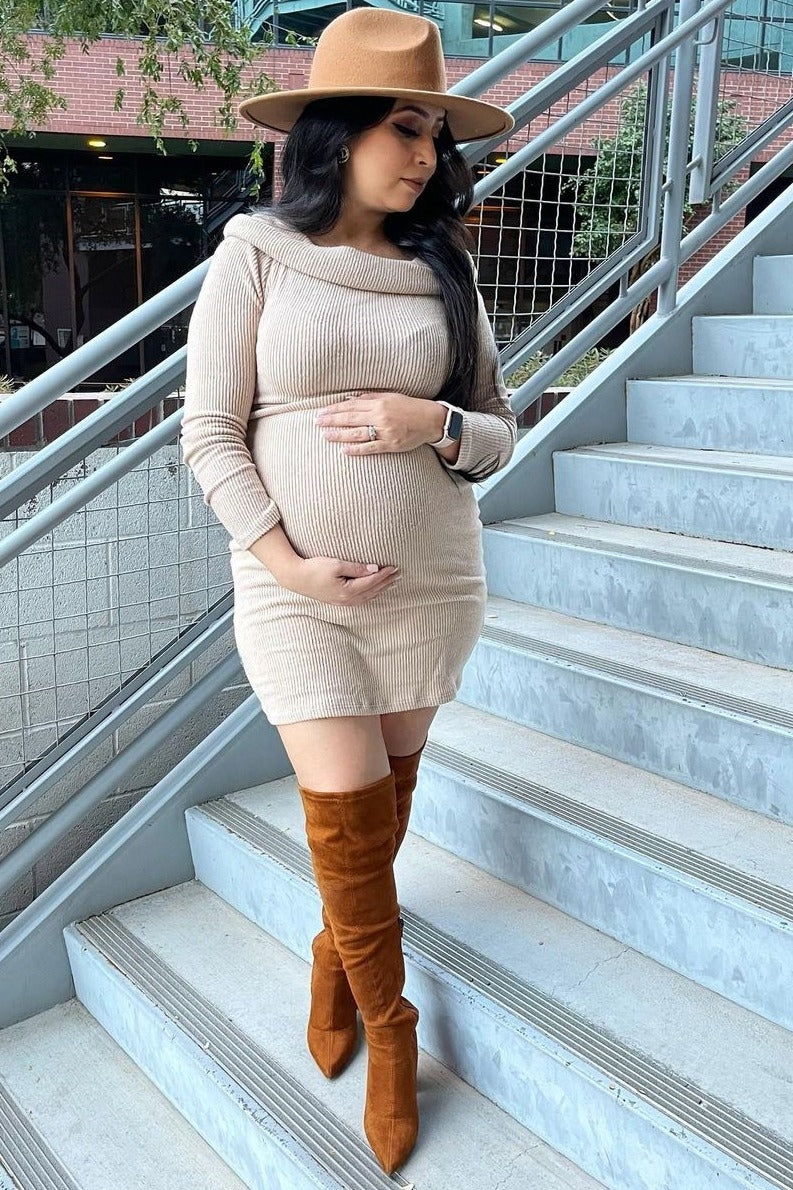 woman wearing a beige ribbed maternity dress and brown over-the-knee boots, showcasing her baby bump